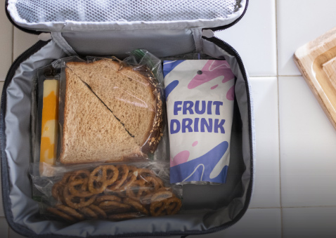 A lunchbox filled with a sandwich, pretzels, and a sugar-sweetened fruit drink.
