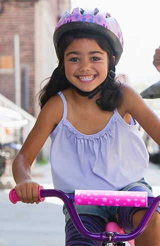 A picture of a smiling girl riding a bike.