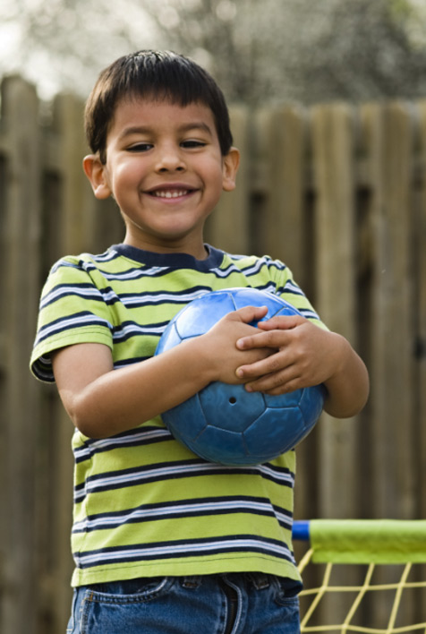 A young boy with short brown hair, holding a blue ball in his hands.