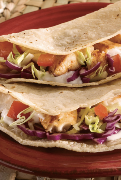 Two tacos on a red plate, garnished with lettuce and cheese, ready to be enjoyed.