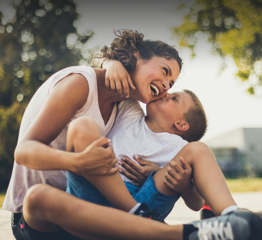 A woman and a boy sitting on the ground, enjoying a peaceful moment together.