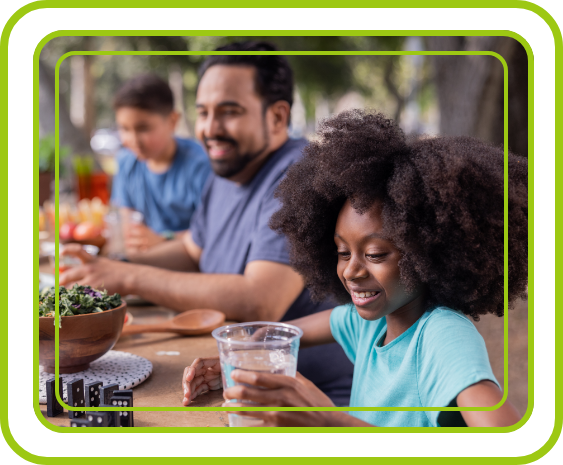 A family chooses water over sugary drinks as kids play, showing the value of healthy eating and staying active.