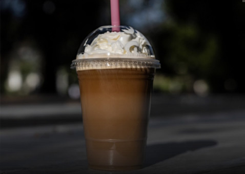 Una taza para llevar de café saborizado con la cantidad de azúcar escrita sobre la imagen.
