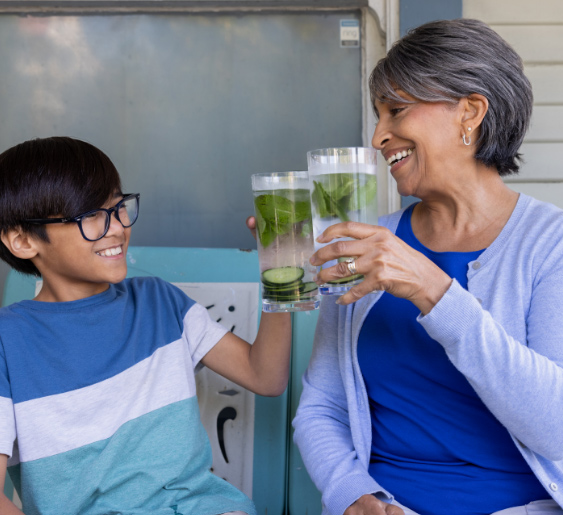 Una mujer y un niño sonriendo, brindando con vasos de agua.