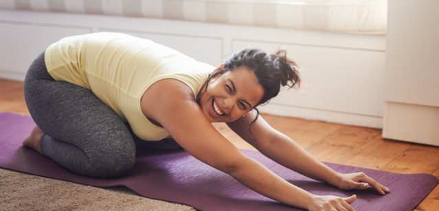 Una mujer practicando yoga en un tapete morado.