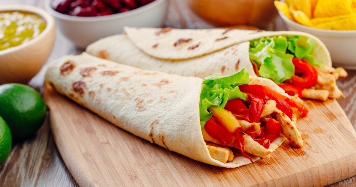 Una tortilla rellena de pollo, pimientos e ingredientes frescos, mostrando una opción de comida saludable y sabrosa.