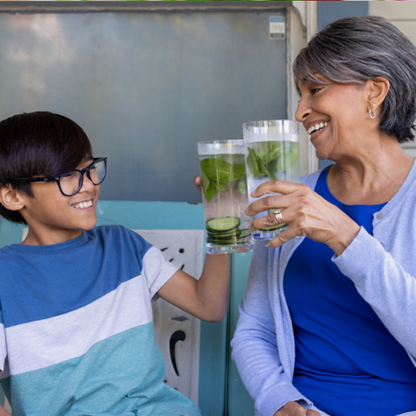 Una mujer y un niño sonriendo, brindando con vasos de agua.